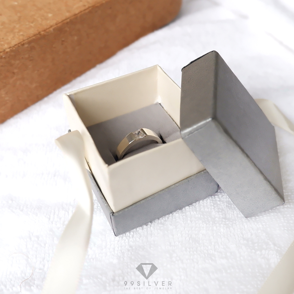 กล่องใส่แหวนสีเทาสี่เหลี่ยมเว้นกลาง มีริบบิ้นผูกโบว์สำหรับยึดฝา ข้างในบุด้วยสปั้นช์นิ่มสีเทา